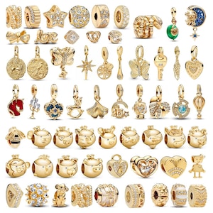 Puede incluir: Una colección de abalorios y colgantes dorados. Los diseños incluyen estrellas, corazones, mariposas y animales. Algunos abalorios están adornados con cristales transparentes. La colección incluye una variedad de formas y tamaños.