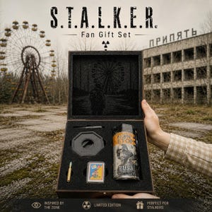 May include: A wooden gift box set with the text "S.T.A.L.K.E.R. Fan Gift Set". The set includes a can with a graphic, a small card, a bullet, and a black object. The background shows a Ferris wheel and a building.