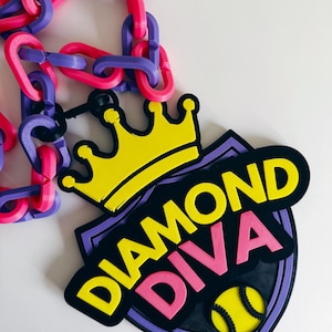 May include: A necklace with a pendant that reads "DIAMOND DIVA" with a yellow crown and a tennis ball graphic. The necklace has a chain made of pink and purple links.