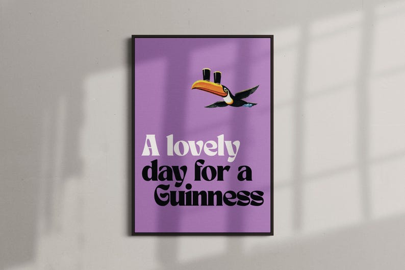 K&ouml;nnte beinhalten: Gerahmtes Poster mit lila Hintergrund. Es zeigt einen Tukan mit zwei Guinness-Pints und dem Text "A lovely day for a Guinness" in Wei&szlig; und Schwarz.