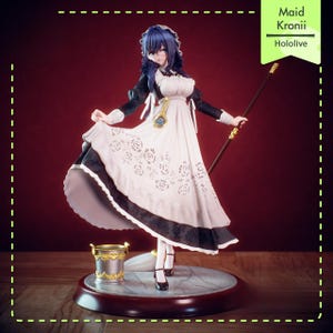 Puede incluir: Figura detallada de un personaje con un atuendo de doncella, sosteniendo un bastón. La figura tiene cabello azul y viste un vestido blanco con detalles en negro y un delantal decorativo. La base incluye un pequeño cubo y el texto "Maid Kronii Hololive".