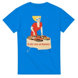 以下が含まれることがあります： 鮮やかなブルーのTシャツ。赤いドレスを着てブロンドの髪をした人物が、様々な料理が並べられたテーブルの後ろに立っているグラフィックイラストが描かれています。テーブルには白いクロスがかけられ、「И это все из Кильки !」という文字が表示されています。