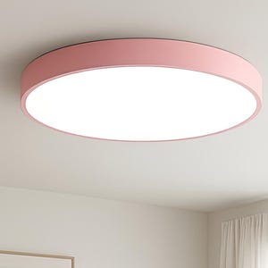 May include: A modern living room featuring a gray sofa with colorful throw pillows, a round wooden coffee table, and a white rug. A pink circular ceiling light illuminates the room. An abstract art print hangs on the wall.