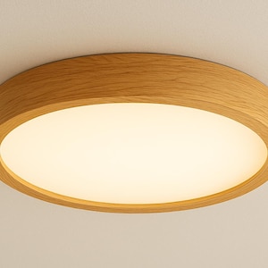 May include: A round, flush-mount ceiling light fixture with a natural wood grain finish. The light has a warm, white glow emanating from a recessed, circular panel. The fixture is mounted on a white ceiling.