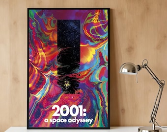 May include: Framed art print featuring the text "2001: a space odyssey." The artwork has a vibrant, colorful, abstract background with a black rectangular shape in the center. A small astronaut figure is visible. The print is displayed on a white surface.