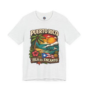 Puede incluir: Camiseta gris claro con un gráfico colorido que representa una escena tropical. El diseño incluye una palmera, olas del océano, una puesta de sol y el texto "Puerto Rico Isla del Encanto". Una flor de hibisco roja, piña y la bandera puertorriqueña también son visibles.