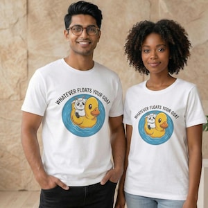 May include: White t-shirts with a graphic of a goat and panda bear riding a yellow duck floatie in a blue circle. The text "WHATEVER FLOATS YOUR GOAT" is printed above the graphic. Two people are wearing the shirts.