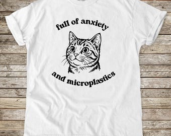 Maglietta con illustrazione di gatto, piena di ansia e microplastiche, maglietta sarcastica e carina, colori confortevoli.