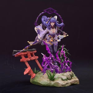 May include: A detailed figurine of a character in a flowing purple and white outfit, holding a spear. The figure stands on a base with a red torii gate and purple energy effects. The character has long purple hair and a determined expression.