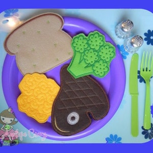 May include: A felt play food set on a purple plate, including a slice of bread, broccoli, a steak, and a chicken nugget. The set also includes a green fork and knife, and two salt shakers. The image has a blue border.