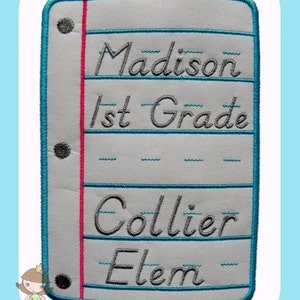 Op de afbeelding: Een witte, papierachtige patch met een blauwe rand en een rode lijn aan de zijkant. De patch heeft een gesimuleerd notitieboekpapierontwerp met lijnen en gaten. De tekst "Madison 1st Grade Collier Elem" is in grijs op de patch geborduurd.