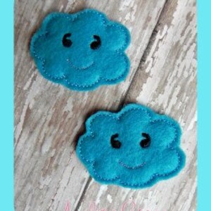 May include: Two teal blue felt cloud shapes with black smiling faces. The clouds are sewn with a simple stitch.