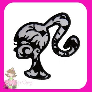May include: Black and white embroidered patch featuring a silhouette of a woman's profile with a ponytail. The design has a decorative, floral-like pattern within the silhouette. The patch is outlined with a black border and is likely for clothing or accessories.