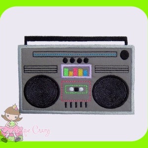 May include: A gray boombox with black speakers, a handle, and a cassette tape compartment. The boombox has a colorful equalizer display and is outlined in black. The image is set against a white background with a green border.