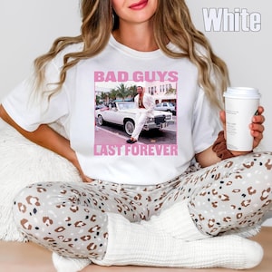 May include: White t-shirt with a graphic featuring a man in a white suit next to a white convertible car. The text "BAD GUYS LAST FOREVER" is printed in pink. The model is wearing leopard print pajama pants.