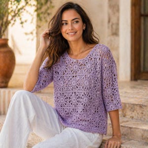 May include: A light purple, open-weave crochet top with three-quarter sleeves. The top features a floral pattern and a scoop neckline. The model is wearing white pants. The top is a lightweight, breathable garment.