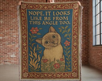 Pode incluir: Uma manta tecida com fundo azul e borda decorativa. A manta apresenta uma ilustração de gato rodeada por flores e o texto "Nope. It looks like BS from this angle too."