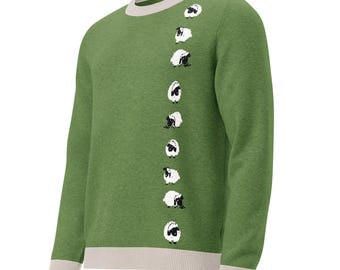 May include: A long-sleeve crewneck sweater in a heathered olive green color. The garment features a vertical row of nine small, white and black sheep illustrations running down the right side of the chest. It has a light beige ribbed collar and cuffs.