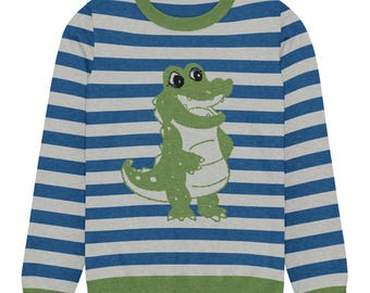 May include: A long-sleeve crewneck sweater featuring horizontal blue and light gray stripes. The garment has a solid olive green ribbed collar and hem. Centered on the front is a graphic illustration of a smiling green crocodile character.