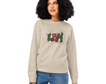 May include: A beige long-sleeve sweatshirt featuring the letters LBM in a stylized green and red font on the chest. The letters are surrounded by a thin, dark, hand-drawn style vine illustration with small red accents.