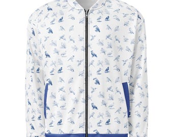 May include: A white bomber jacket featuring a repeating pattern of blue bird illustrations. The jacket has a full-length black front zipper, a ribbed collar, and a solid blue band along the bottom hem and the openings of the two front pockets.