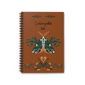 Può includere: Quaderno a spirale con copertina marrone con un motivo decorativo a falena in verde acqua, bianco e arancione. Il testo "Customizable text" è sopra la falena. Accenti floreali e di foglie completano il design.