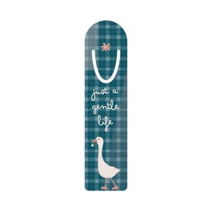 Könnte beinhalten: Türkis-weiß karierter Lesezeichen mit einer weißen Gans, die eine Blume hält. Der Lesezeichen hat den Text "just a gentle life" in Schreibschrift. Oben befindet sich eine kleine rosa Blume.