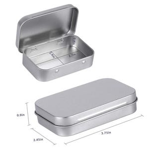 May include: Two small, rectangular, silver-colored metal tins. One tin is open, revealing the interior, and the other is closed. The open tin measures 3.7 inches long, 2.4 inches wide, and 0.8 inches deep. The closed tin is 3.75 inches long, 2.45 inches wide, and 0.9 inches high.