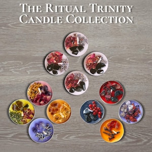 Könnte beinhalten: The Ritual Trinity Candle Collection. Eine Sammlung runder Kerzen in verschiedenen Farben, jede dekoriert mit getrockneten Blumen, Kristallen und schwarzen Steinen. Die Kerzen sind auf einer Holzoberfläche angeordnet.