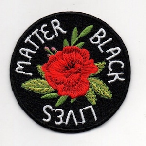 May include: Black Lives Matter embroidered patch with a red flower and green leaves on a black background.
