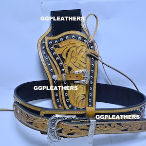 Może przedstawiać: Zestaw skórzanej kabury i paska w stylu western. Kabura jest czarna i brązowa z srebrnymi ćwiekami i kwiatowym wzorem. Pasek jest czarny z pasującym kwiatowym wzorem i srebrną klamrą.