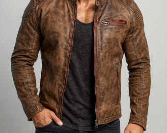 May include: Brown leather jacket with a distressed finish, featuring a stand-up collar and red zipper accents. The jacket has quilted shoulder detailing and a classic biker style. The model is wearing a black shirt and dark jeans.