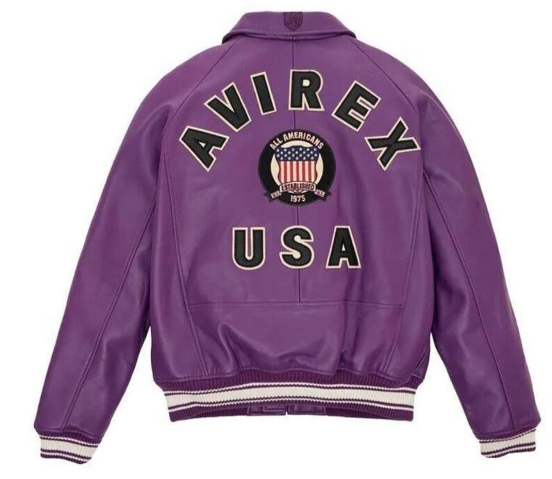 May include: A purple leather jacket with the word "AVIREX" arched across the shoulders. Below the word "AVIREX" is a patch with the words "ALL AMERICANS ESTABLISHED 1975" and a US flag design. The word "USA" is below the patch.