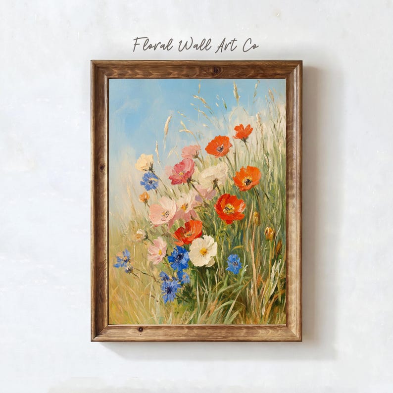 A single floral meadow painting with red poppies, pale pink blossoms, white flowers, and blue cornflower-like accents rising through tall grasses under an open blue sky. The brushwork is loose and painterly, with a bright but still vintage-inspired palette that softens the stronger reds and blues with warm cream and green. The artwork brings a fresh countryside note to the French country printable bundle while staying romantic, classic, and collected.