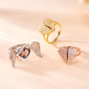 May include: Three rings with heart and wing designs. One is silver with a photo inside and the words "ways and forever". Another is gold with "Love you always" inscribed. The third is rose gold.