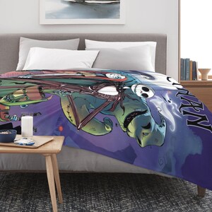 May include: A plush blanket featuring characters from "The Nightmare Before Christmas." The design includes Jack Skellington, Sally, and Oogie Boogie against a purple and blue background. The word "HALLOWEEN" is visible.