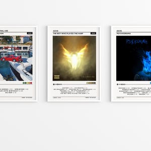 May include: Three framed album art prints. The first shows a red car on a dock, the second a glowing angel, and the third a blue flame face. Each print includes the artist's name, album title, and tracklist.