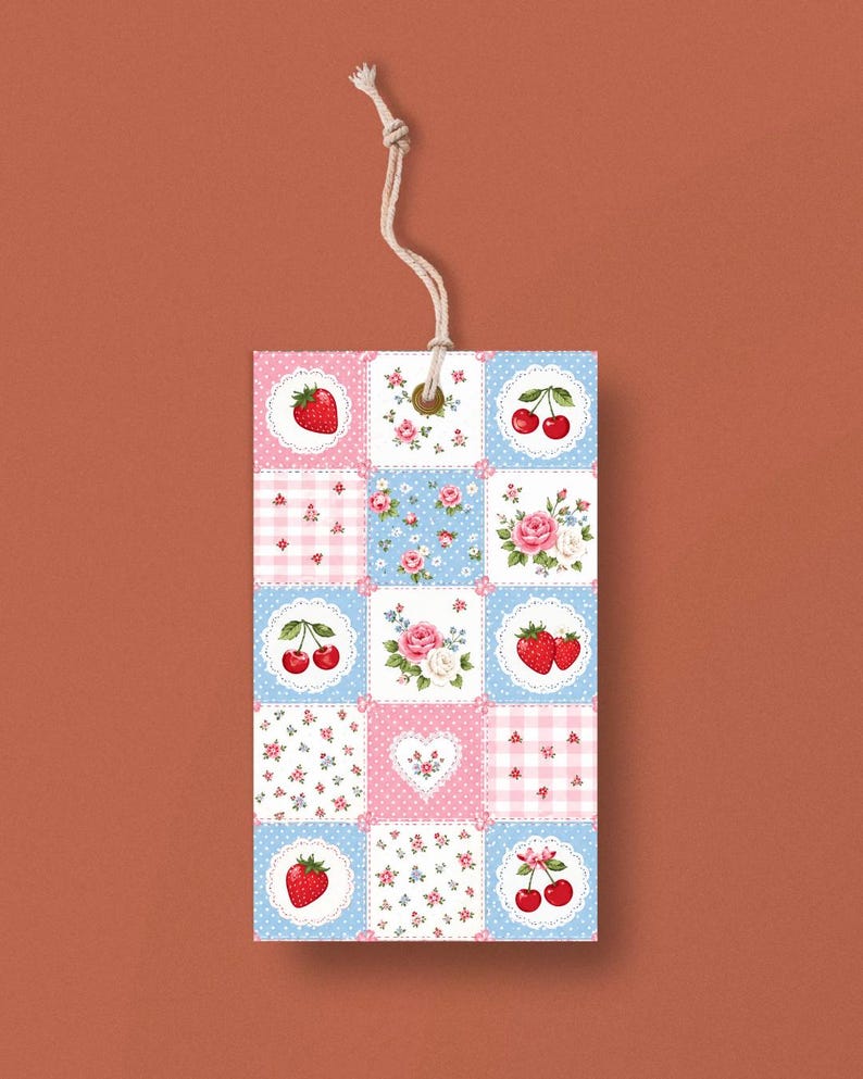 May include: A rectangular tag with a patchwork design featuring strawberries, cherries, and roses on a blue and pink background. The tag is made of paper and has a natural twine string attached at the top.