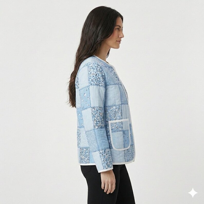 May include: A light blue patchwork jacket with a white trim and two front pockets. The jacket features a variety of blue patterned squares. The jacket is worn over a white top and black pants.