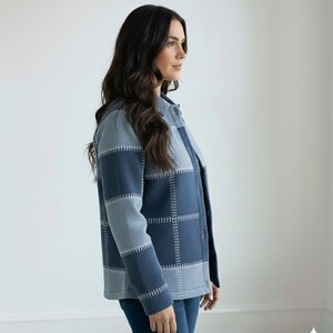 May include: A blue and grey patchwork jacket with a button-up front. The jacket has a plaid design with visible stitching. The sleeves are long, and the jacket is worn with blue jeans. The overall style is casual and comfortable.