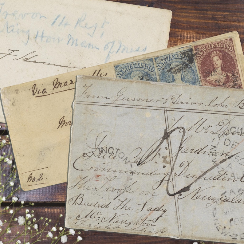 May include: Three vintage paper envelopes with handwritten cursive addresses and postmarks. One envelope features a red New Zealand postage stamp depicting a portrait, while another is marked with the text No. 2 and Via Marseille in black ink.