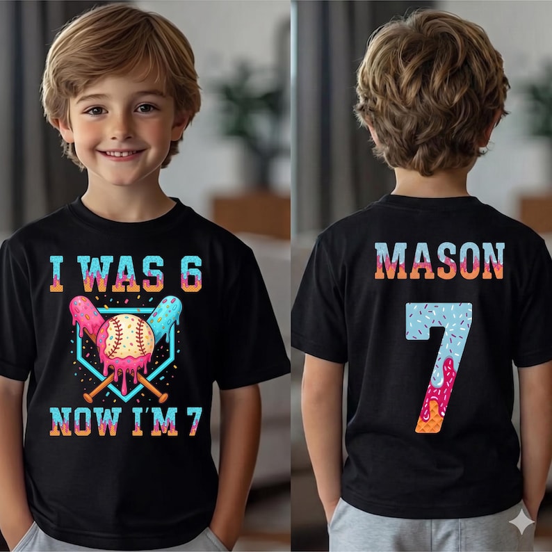 May include: Black t-shirt with a colorful baseball-themed graphic. The front reads "I WAS 6 NOW I'M 7" with a baseball and ice cream design. The back has the name "MASON" and the number "7".