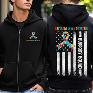 May include: Black zip-up hoodie with "Autism Awareness" text and a colorful ribbon graphic on the front. The back features a flag design with the text "Autism Awareness" and "Support Squad."