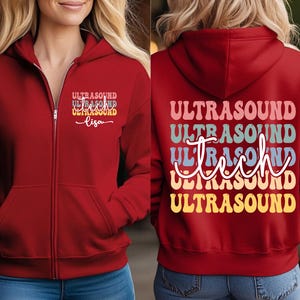 May include: A red zip-up hoodie with the text "ULTRASOUND" in a retro font on the front and back. The front also has the name "Lisa" below the text. The hoodie has a hood and pockets.