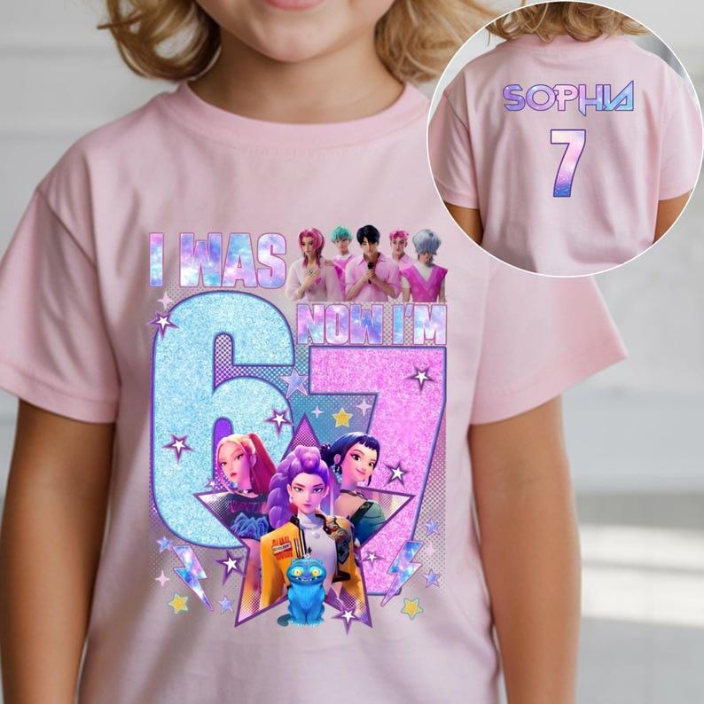 May include: A light pink t-shirt with the text "I WAS 6 NOW I'M 7" in a blue and purple design. The shirt features a graphic of animated characters and stars. The back of the shirt has the name "SOPHIA" and the number "7".