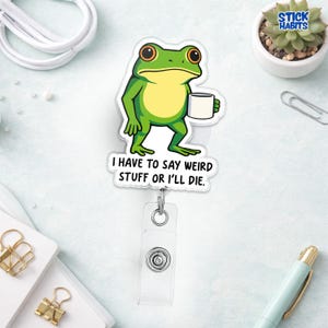 May include: A green and yellow frog cartoon badge reel with the text "I HAVE TO SAY WEIRD STUFF OR I'LL DIE." The frog is holding a white mug. The badge reel has a clear plastic holder and a metal clip.