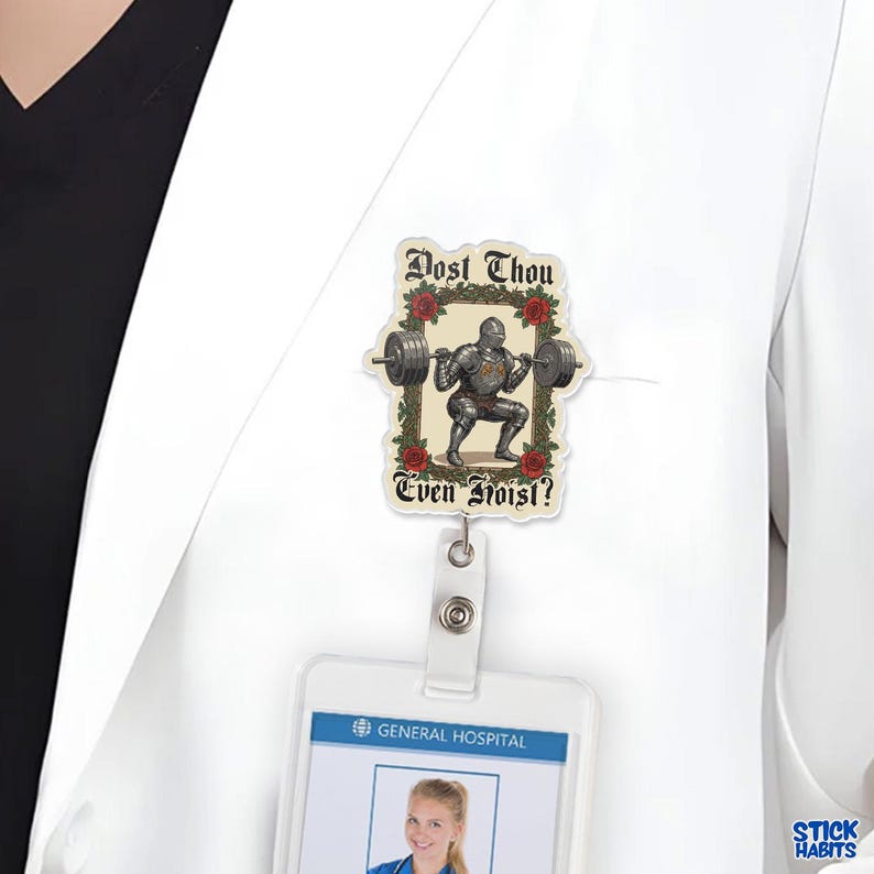 Op de afbeelding: Een rechthoekige badge reel met een ridder die gewichten heft, omringd door rozen. De tekst "Dost Thou Even Hoist?" staat in een decoratief lettertype. De badge reel is bevestigd aan een witte labjas.