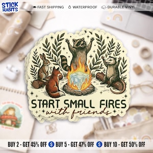 May include: A sticker featuring a campfire scene with a raccoon, opossum, fox, and rabbit. The text "START SMALL FIRES with friends" is below the illustration. The sticker is beige with a white border.