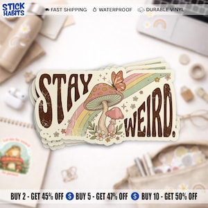 May include: A stack of rectangular stickers with the words "STAY WEIRD" in brown, vintage-style lettering. The design features a mushroom, rainbow, and butterfly. The stickers are on a white surface.