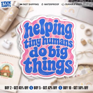 May include: A die-cut vinyl sticker featuring the blue text "helping tiny humans do big things" in a retro, wavy font. The lettering is set against a pink and white swirled background with a distressed, textured finish on the blue letters.